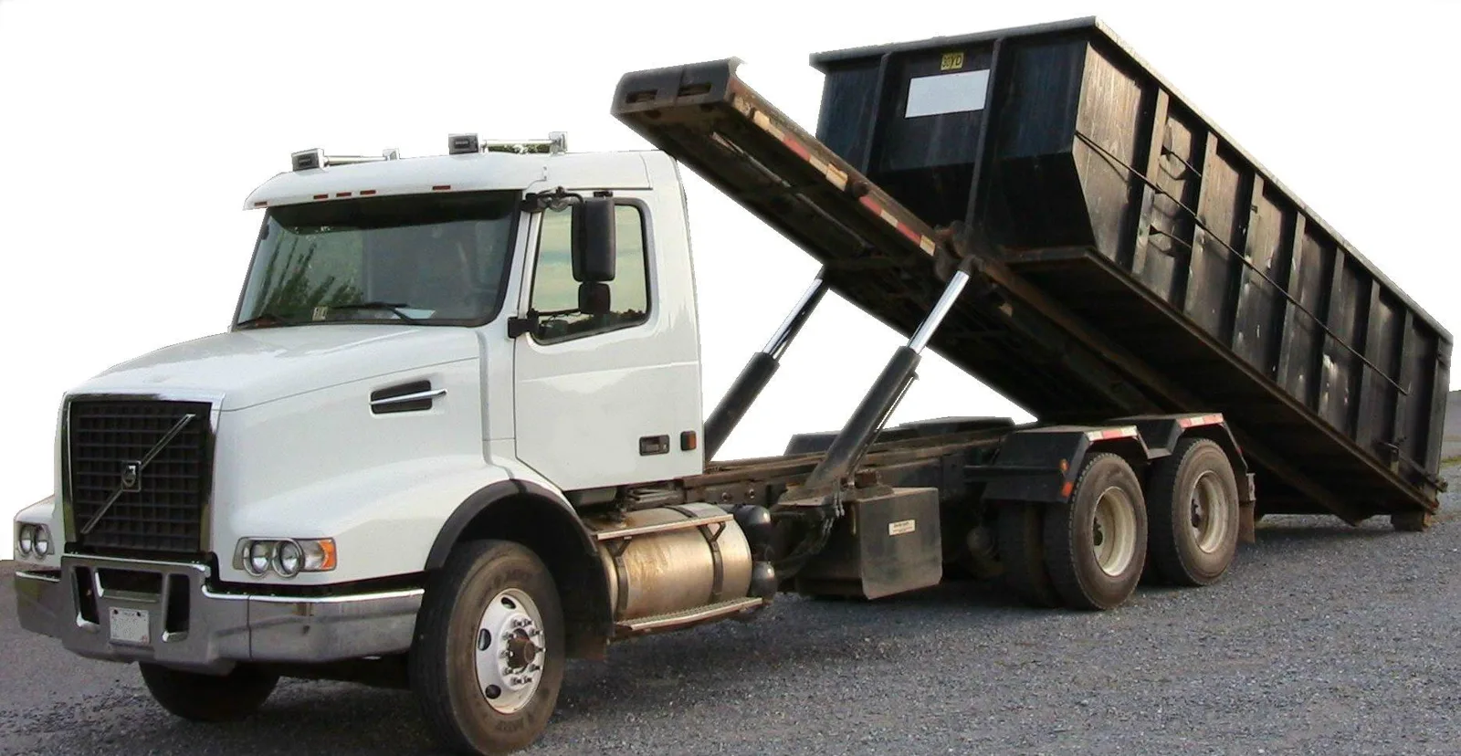 Roll-off truck tilting its hoist to set down a tall open-top roll-off container